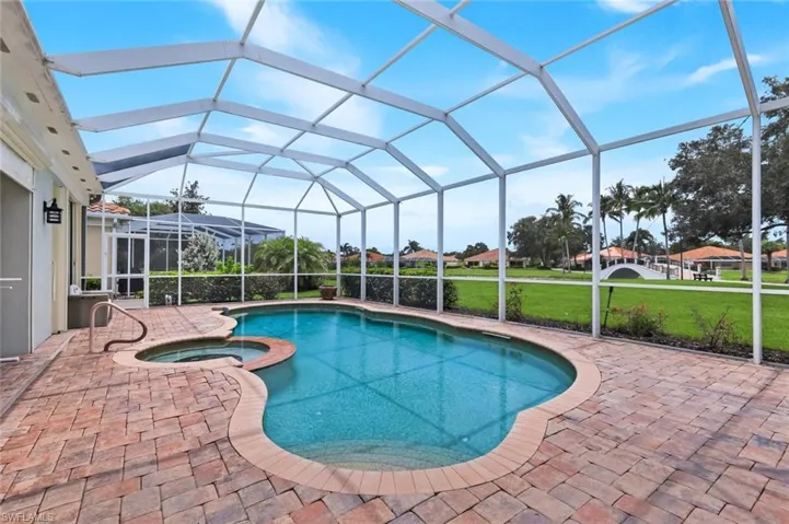 Exterior featuring a tile roof, paved driveway, two-car garage, and established landscaping