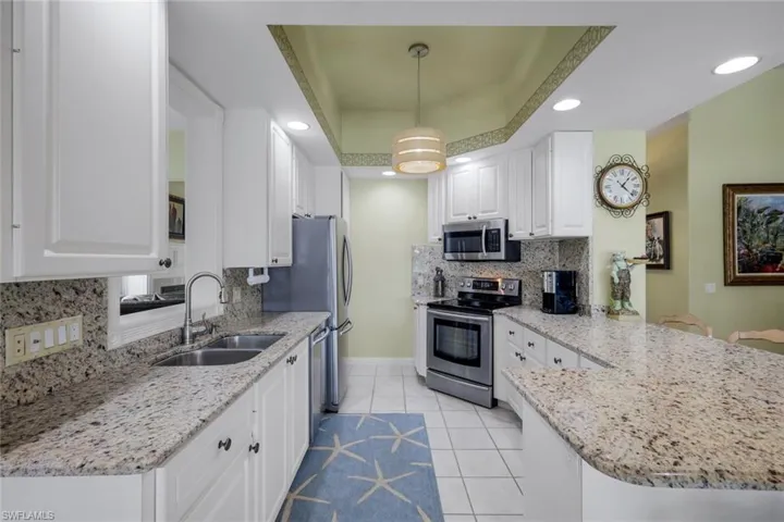 Open-concept kitchen featuring an island with granite countertops, white cabinetry, stainless steel appliances, and recessed lighting