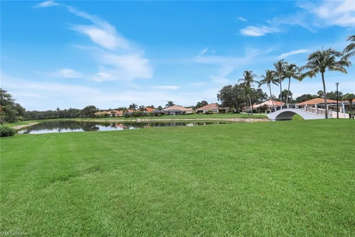 Aerial exterior featuring a terracotta tile roof, screened swimming pool enclosure, solar panels, mature landscaping, and an expansive rear lawn