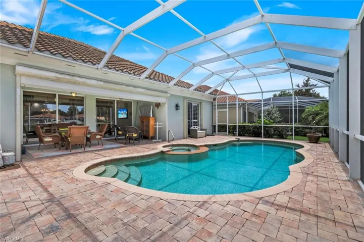 Screened-in pool area featuring a freeform swimming pool with integrated spa