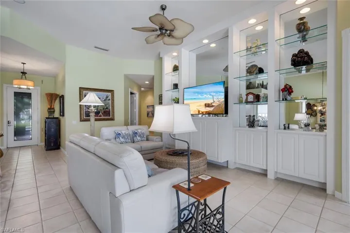 Spacious open-concept living area featuring a ceiling fan, light-toned tile flooring, and vaulted ceilings