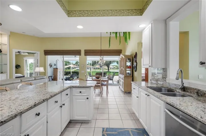 Open-concept living space featuring a dining area with an ornate chandelier and a kitchen with white cabinetry, stainless steel appliances, and a breakfast bar with seating