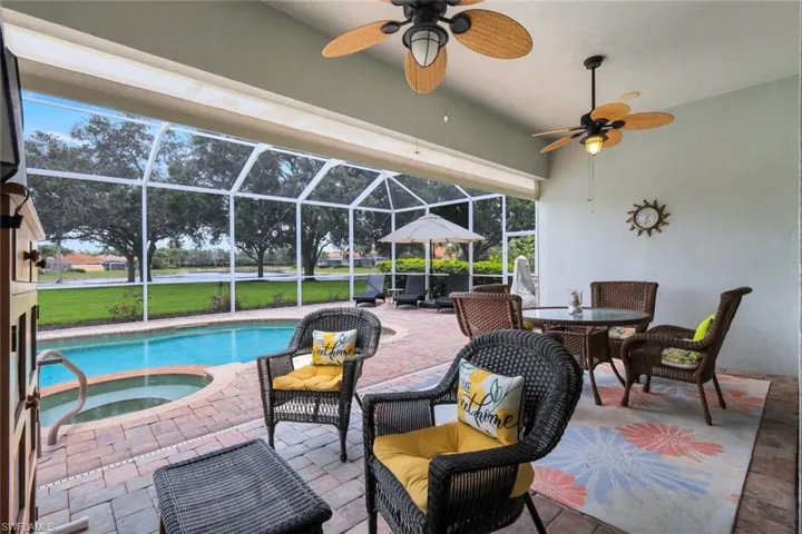 Screened outdoor living area featuring a freeform swimming pool with integrated spa and paver decking