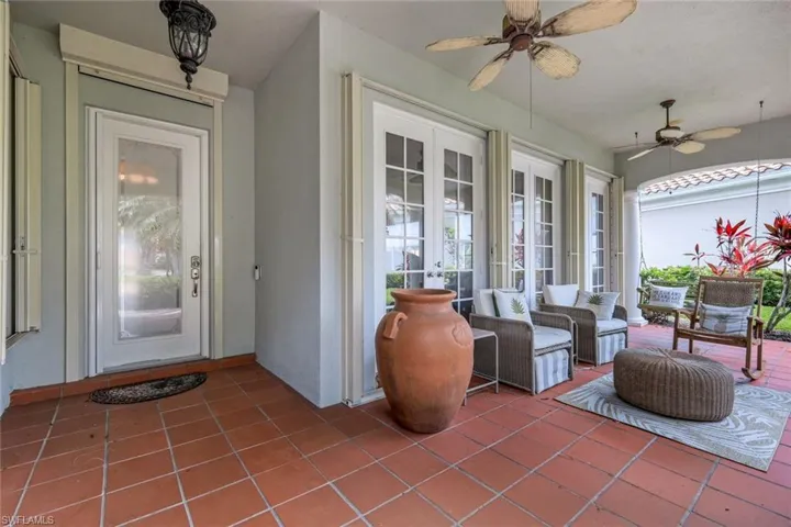 Spacious main living area featuring tile flooring, vaulted ceilings, a ceiling fan, and sliding glass doors opening to the exterior patio