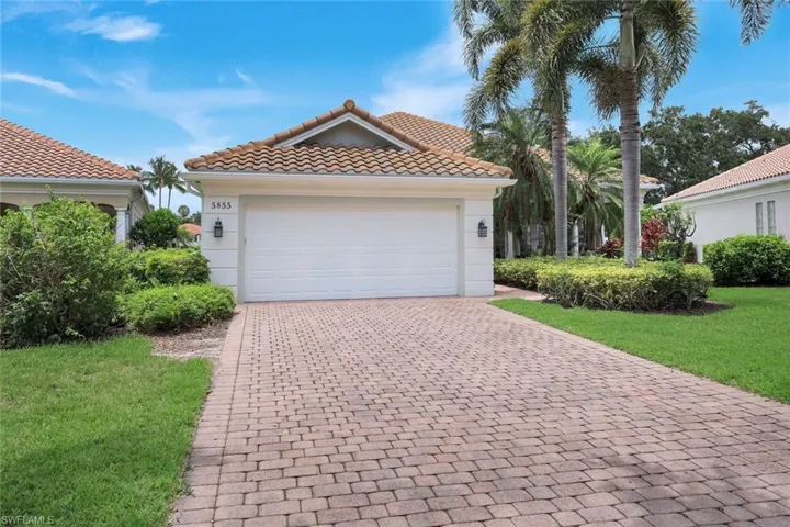 Aerial property overview featuring a terracotta tile roof, screened lanai, and lush tropical landscaping