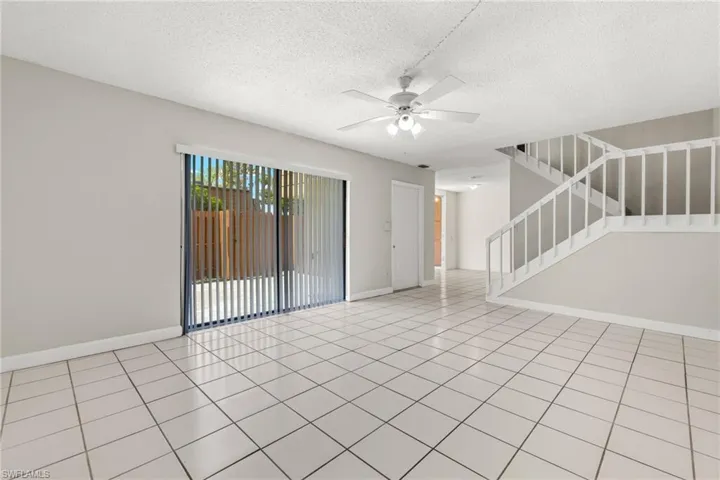 Spare room with a textured ceiling, stairway, light tile patterned flooring, and ceiling fan