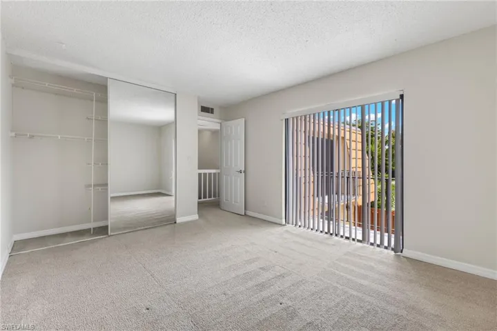 Unfurnished bedroom with a textured ceiling, light carpet, and a closet
