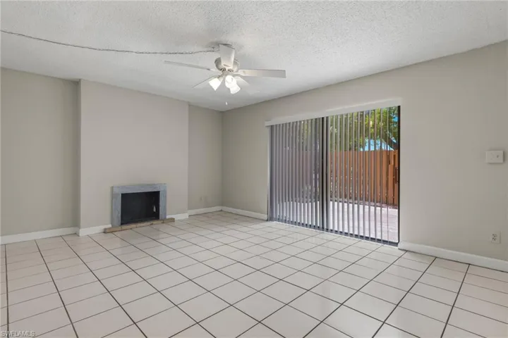 Unfurnished living room featuring a textured ceiling, light tile patterned floors, a fireplace, and a ceiling fan