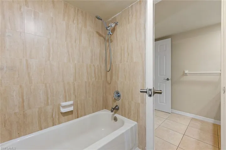 Full bath with washtub / shower combination and tile patterned floors