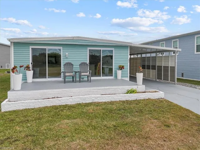 Rear view of house featuring a yard, a carport, and a patio area