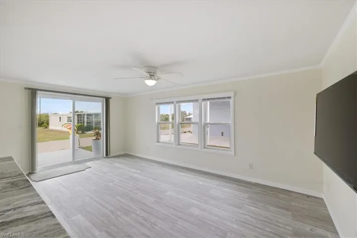 Unfurnished living room featuring crown molding, light wood finished floors, and a ceiling fan