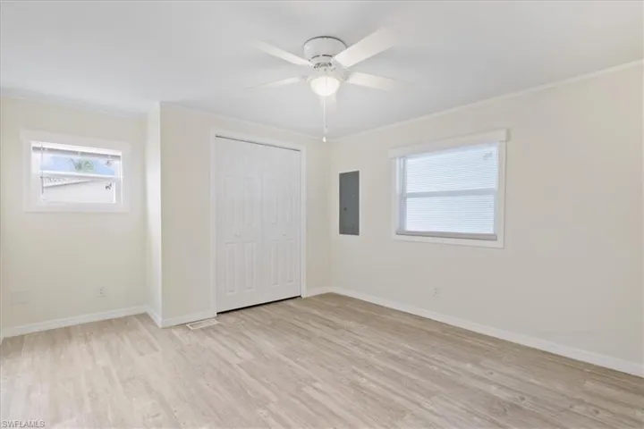 Unfurnished bedroom with light wood-type flooring, a closet, crown molding, electric panel, and ceiling fan