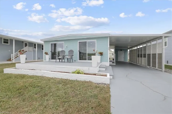 Rear view of house with a patio area, a yard, concrete driveway, and an attached carport