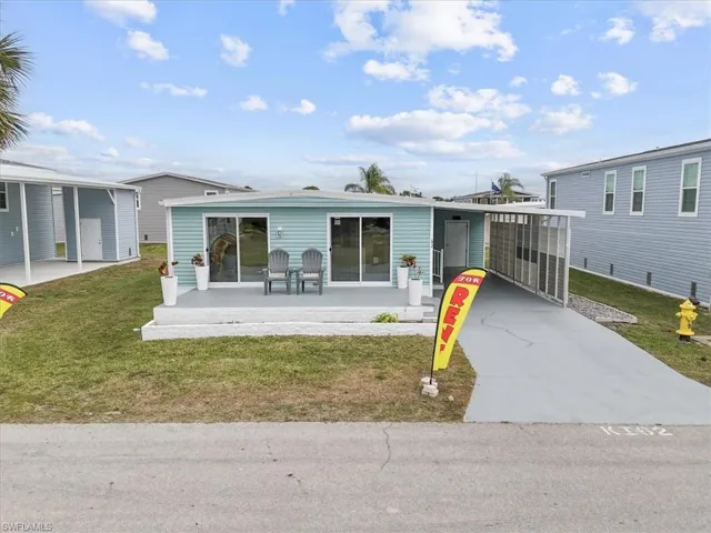 View of front of house featuring a front yard, a carport, and driveway
