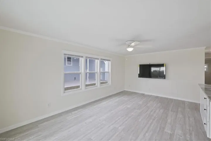 Unfurnished room featuring ornamental molding, light wood finished floors, and a ceiling fan