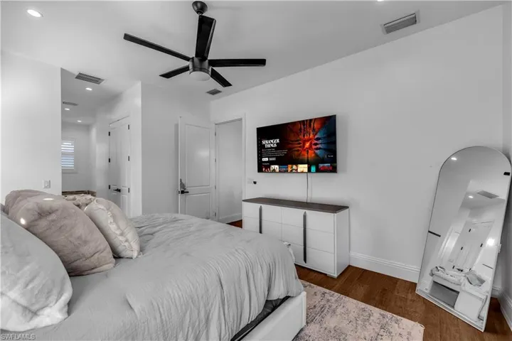 Bedroom with recessed lighting, ensuite bathroom, dark wood finished floors, arched walkways, and a ceiling fan