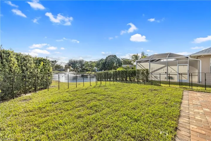 Fenced backyard featuring a water view and glass enclosure