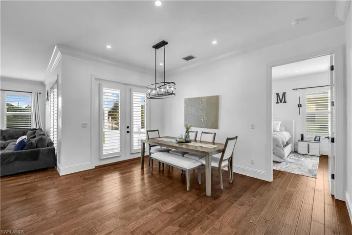 Dining space featuring ornamental molding, dark wood-style flooring, and hanging lights