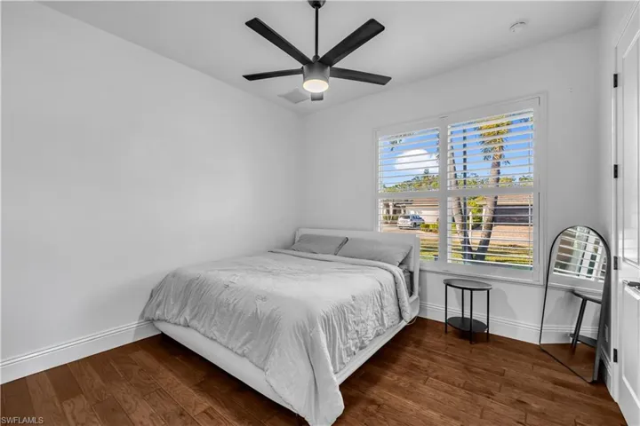 Bedroom with dark wood-type flooring and a ceiling fan