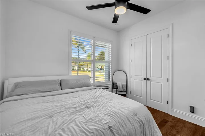 Bedroom with dark wood-style flooring, a closet, and a ceiling fan