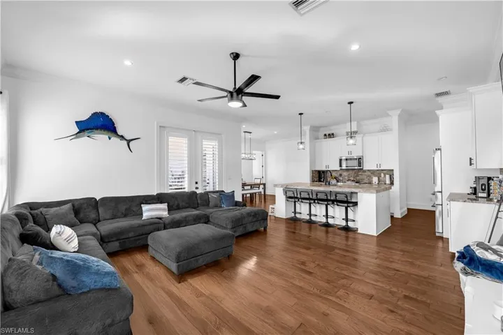Living room featuring ornamental molding, dark wood-style flooring, ceiling fan, french doors, and recessed lighting