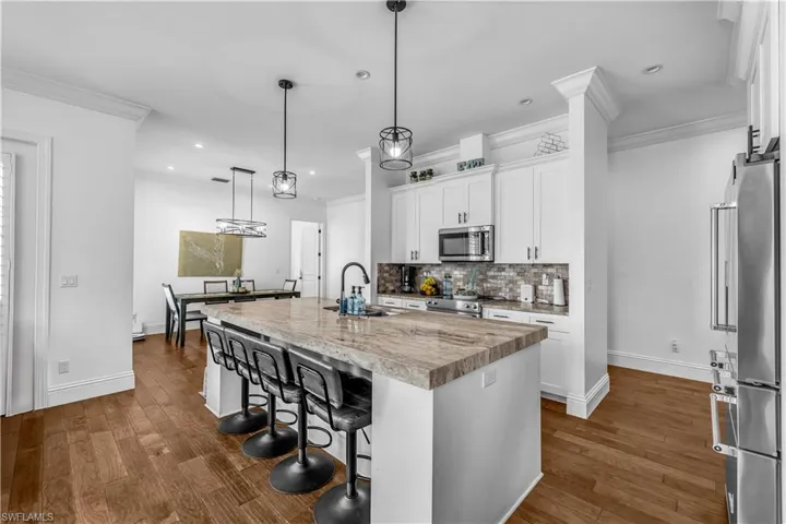 Kitchen with a kitchen bar, light countertops, white cabinets, high end appliances, and dark wood-style flooring