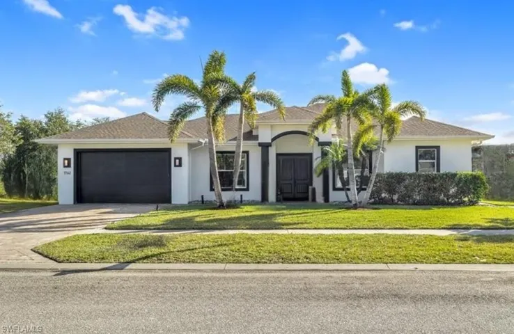 Ranch-style house featuring stucco siding, driveway, an attached garage, and a front lawn
