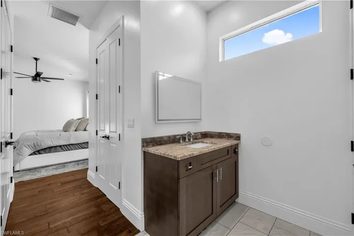 Ensuite bathroom featuring vanity, a ceiling fan, and light wood-style flooring