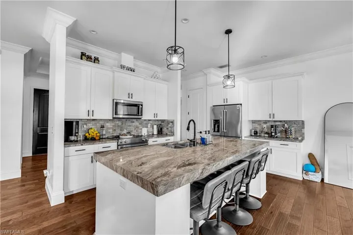 Kitchen featuring backsplash, a breakfast bar, white cabinets, ornamental molding, and high end appliances