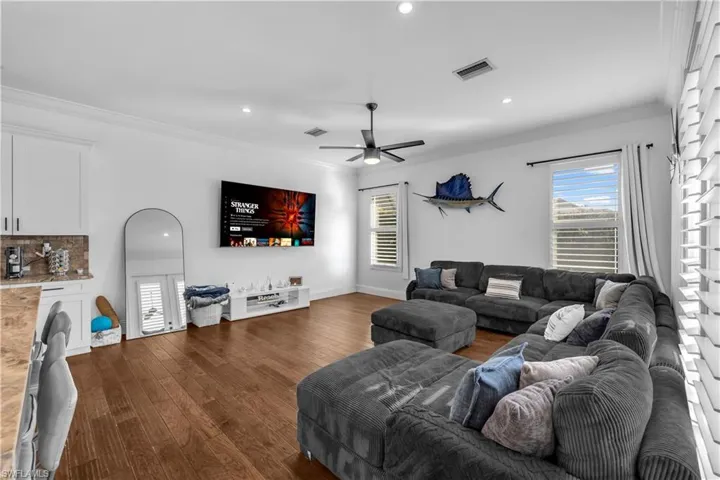 Living room featuring ornamental molding, recessed lighting, dark wood-style floors, and a ceiling fan
