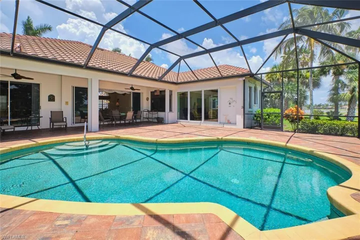 Outdoor pool featuring a water view, a patio area, and glass enclosure