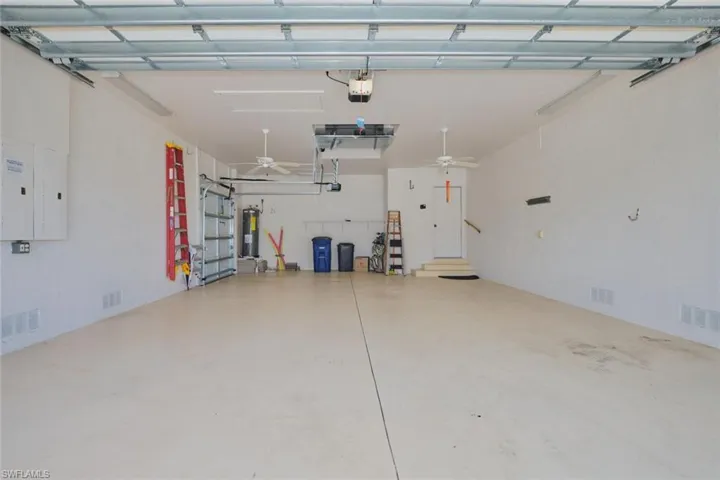 Garage with electric panel, ceiling fan, and electric water heater