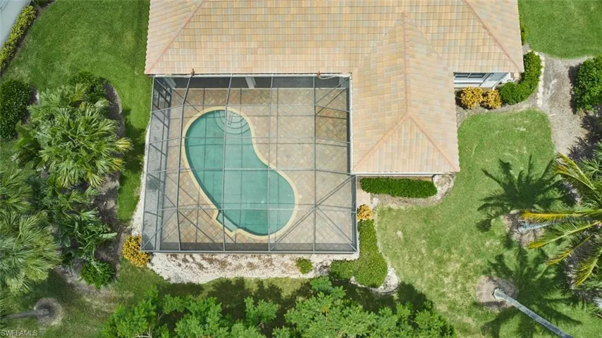 View of grassy yard with a water view and glass enclosure