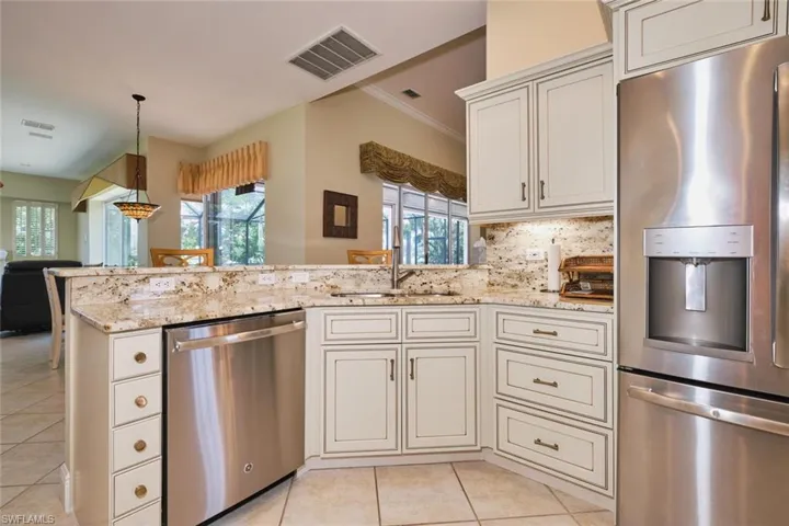 Kitchen featuring stainless steel appliances, decorative backsplash, a peninsula, healthy amount of natural light, and ornamental molding