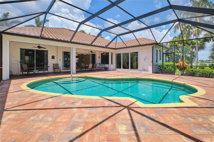 Outdoor pool with a patio area, a water view, and glass enclosure
