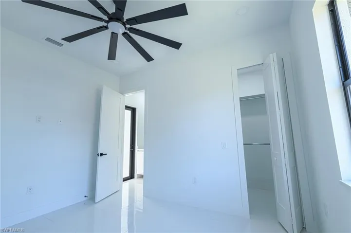 Unfurnished bedroom with a walk in closet and a ceiling fan
