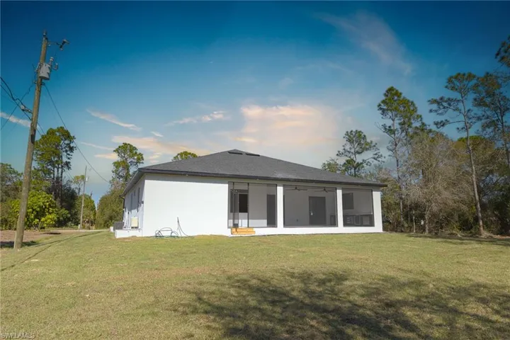 Rear view of house featuring ceiling fan, a yard, and a sunroom
