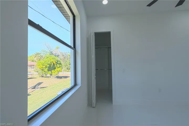 Unfurnished bedroom with a spacious closet, tile patterned flooring, recessed lighting, and a ceiling fan