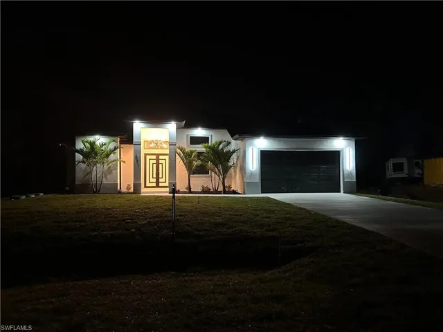 View of front of home with driveway, stucco siding, a yard, and a garage