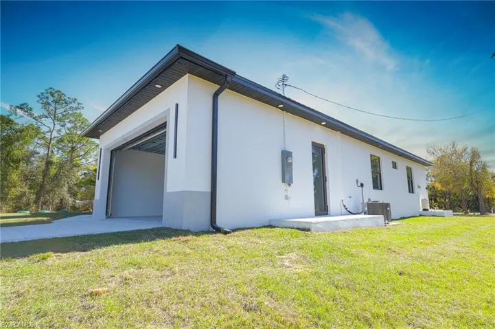 View of property exterior featuring a yard, stucco siding, driveway, and an attached garage