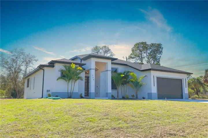 Prairie-style home with a yard, a garage, stucco siding, and concrete driveway