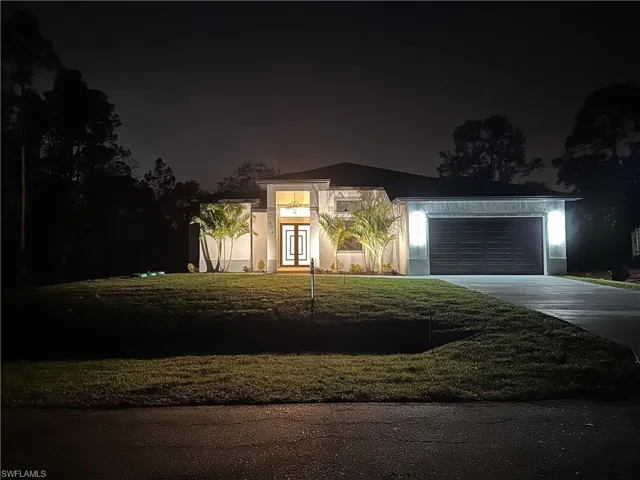 View of front of home featuring driveway, an attached garage, stucco siding, and a lawn