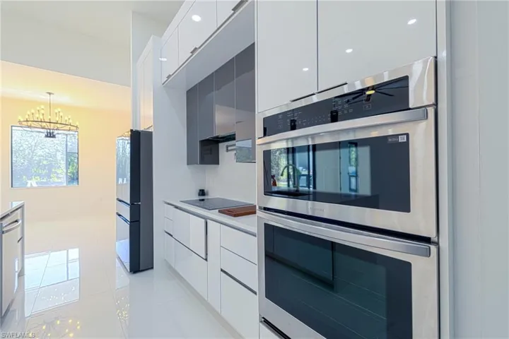 Kitchen with modern cabinets, double oven, light tile patterned floors, and freestanding refrigerator