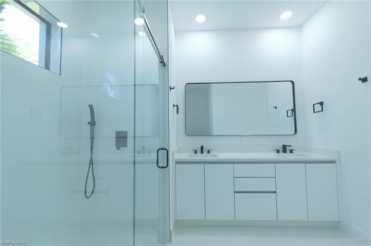 Bathroom featuring a shower stall and double vanity
