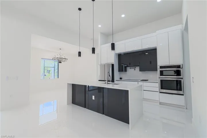 Kitchen with white cabinetry, modern cabinets, pendant lighting, a kitchen island with sink, and light stone counters