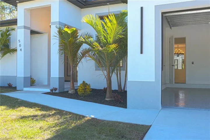 View of exterior entry with stucco siding and a lawn