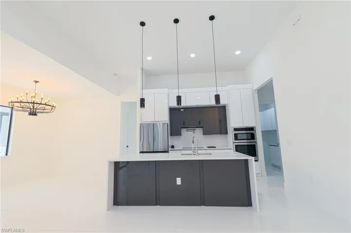 Kitchen with white cabinets, hanging light fixtures, modern cabinets, a spacious island, and stainless steel appliances