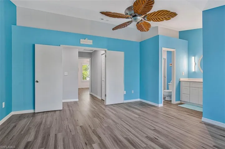 Unfurnished bedroom with light wood-type flooring, ceiling fan, and connected bathroom