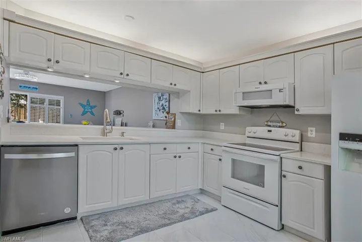 Kitchen with white appliances, white cabinets, and light stone countertops