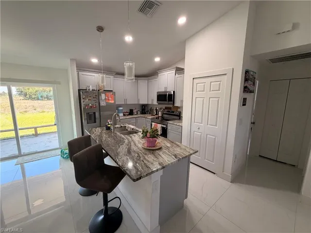 Contemporary kitchen featuring light gray cabinetry, stainless steel appliances, and a central island with a patterned countertop
